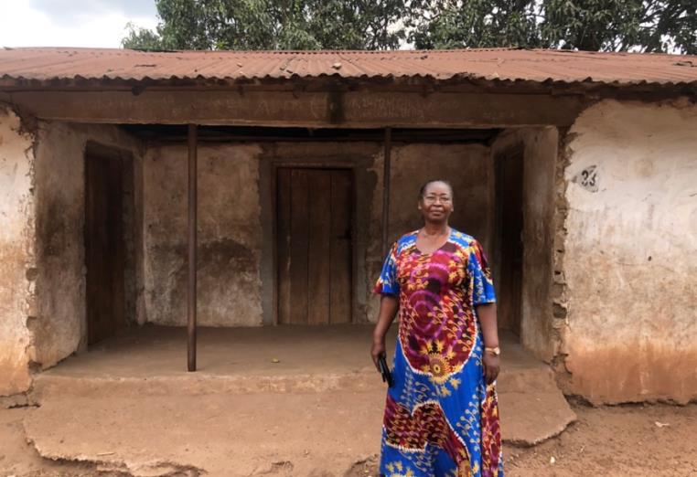 Voorzitter Mrs. Mariatu Fofanah voor de ingang van de school.